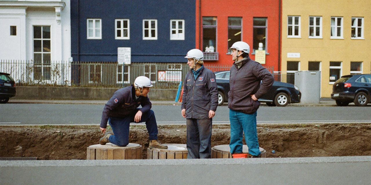 Kabelmonteurs met helm bij een opengebroken sleuf in de straat, met kabelhaspels